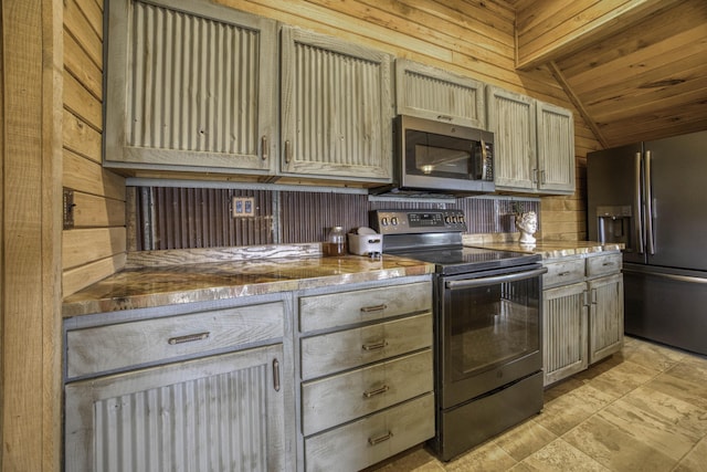 kitchen featuring appliances with stainless steel finishes, lofted ceiling, wood walls, and wood ceiling