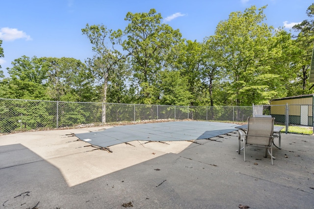 view of pool with fence, a patio, and view of wooded area