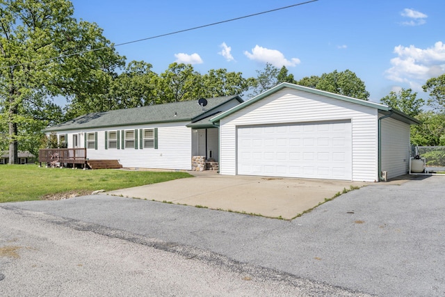 ranch-style house with a front yard, an attached garage, a deck, and driveway