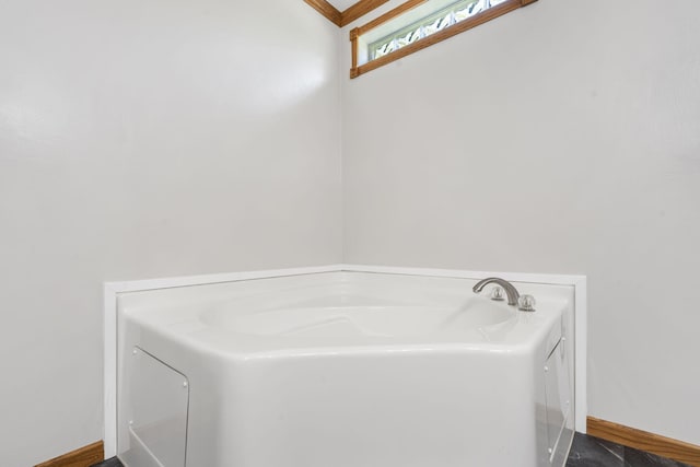 bathroom featuring a bath and baseboards
