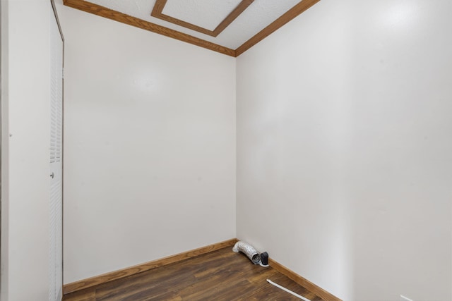 empty room with dark wood finished floors, crown molding, and baseboards
