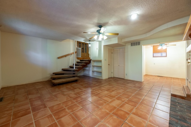 spare room with ceiling fan, stairs, a textured ceiling, and light tile patterned flooring