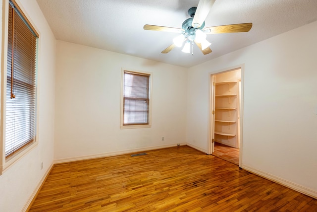 unfurnished bedroom featuring a closet, wood finished floors, baseboards, and ceiling fan