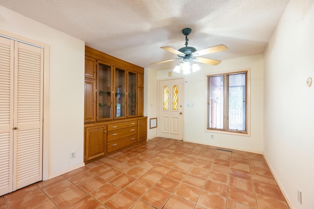 entrance foyer with a ceiling fan, baseboards, and a textured ceiling