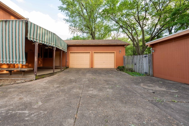 view of property exterior with driveway, an attached garage, and fence