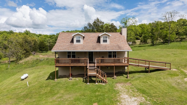 rear view of house featuring a chimney, a deck, and a yard