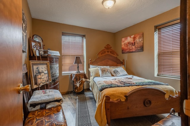 bedroom with hardwood / wood-style flooring, baseboards, and a textured ceiling