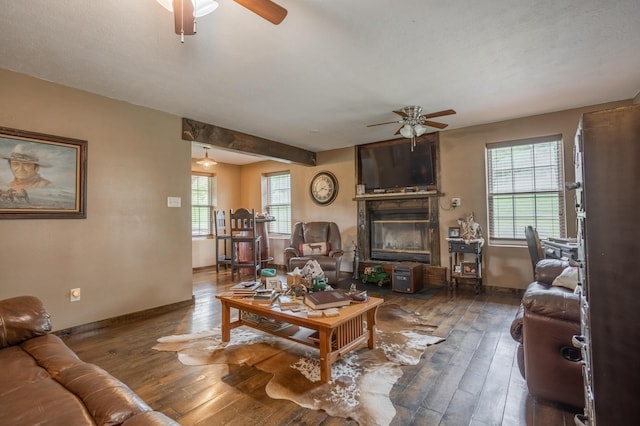 living area featuring ceiling fan, a glass covered fireplace, hardwood / wood-style flooring, and baseboards