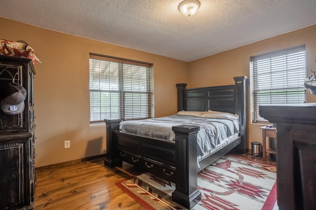 bedroom with wood finished floors, multiple windows, and a textured ceiling