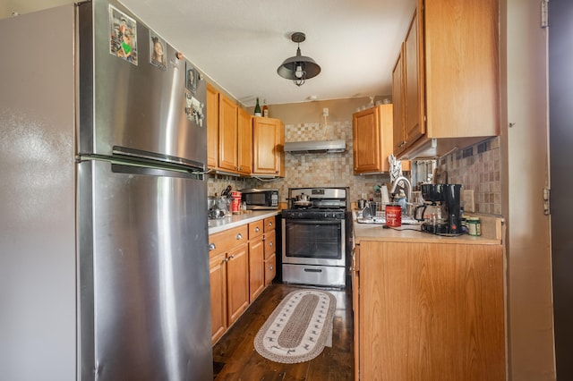 kitchen with stainless steel appliances, under cabinet range hood, light countertops, and decorative backsplash
