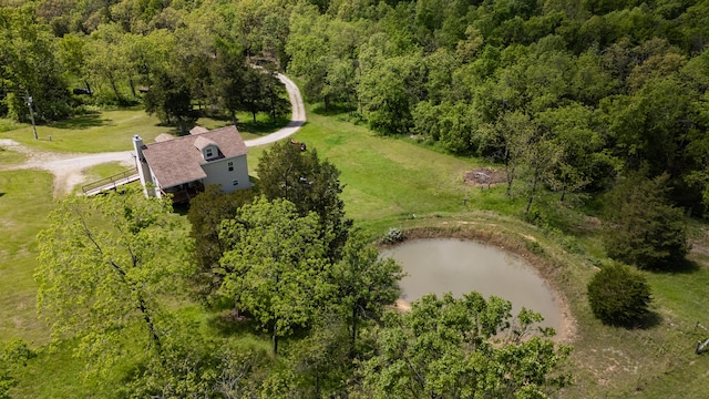 view from above of property with a nearby body of water and a heavily wooded area