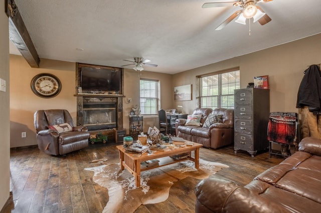 living area featuring a ceiling fan, a large fireplace, and hardwood / wood-style flooring