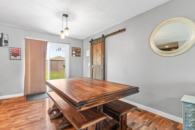 dining room featuring baseboards, wood finished floors, and a barn door