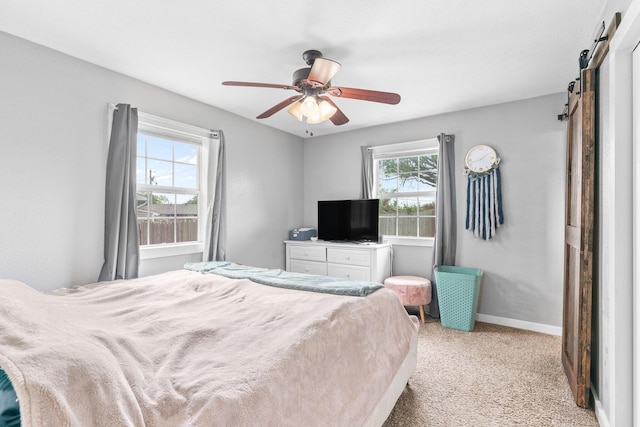 bedroom featuring a barn door, light carpet, baseboards, and a ceiling fan