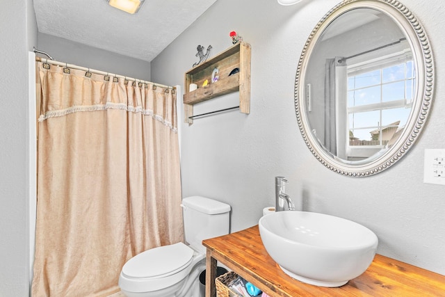 full bathroom featuring a sink, toilet, a shower with shower curtain, and a textured ceiling
