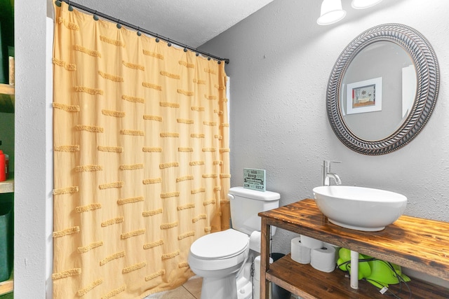 bathroom with a sink, toilet, and tile patterned flooring