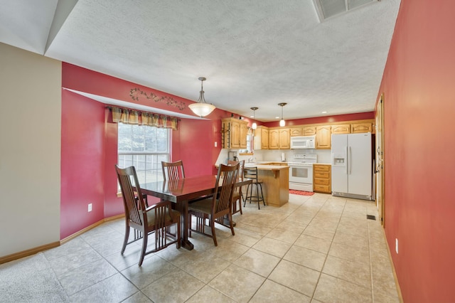 dining space with a textured ceiling, baseboards, and light tile patterned floors