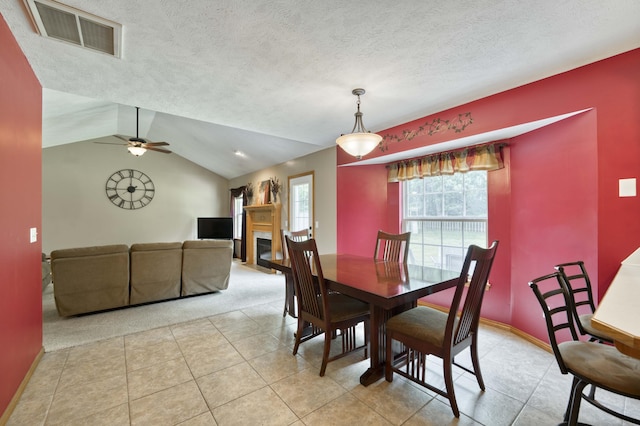 dining area featuring a fireplace with flush hearth, light colored carpet, a ceiling fan, light tile patterned flooring, and lofted ceiling
