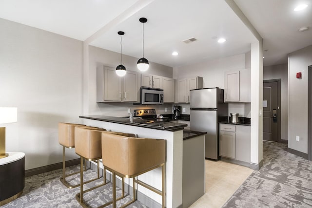 2513A Branson Landing Blvd, Branson, MO 65616 - kitchen with appliances with stainless steel finishes, dark countertops, a peninsula, gray cabinets, and a kitchen bar