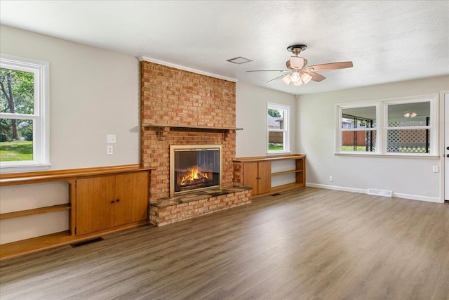 3156 N National Ave, Springfield, MO 65803 - unfurnished living room featuring wood finished floors, a brick fireplace, a ceiling fan, and healthy amount of natural light