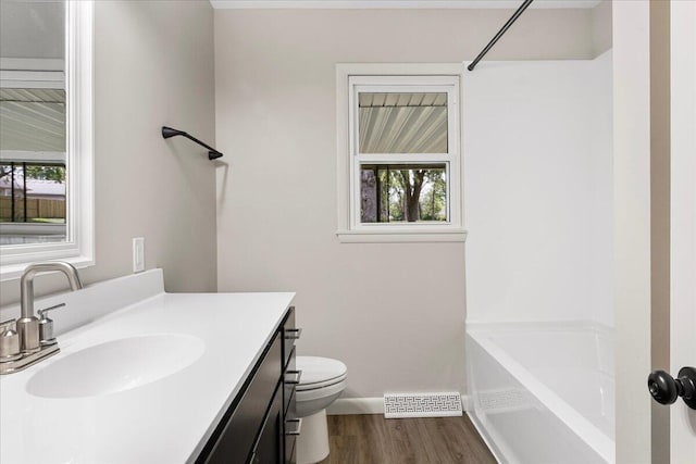 3156 N National Ave, Springfield, MO 65803 - bathroom with wood finished floors, toilet, a tub to relax in, baseboards, and vanity