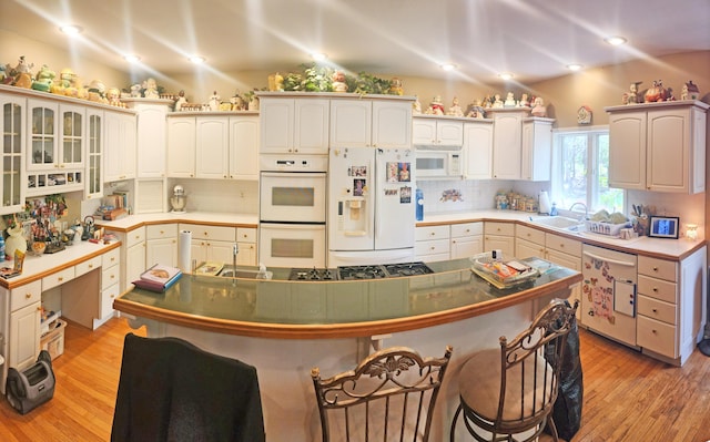 2016 Timberlake Rd, Branson, MO 65616 - kitchen with white appliances, a breakfast bar area, light wood-type flooring, tasteful backsplash, and recessed lighting