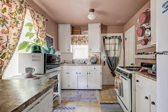 817 Kentland Dr, Neosho, MO 64850 - kitchen featuring gas range oven, light floors, white cabinets, and freestanding refrigerator