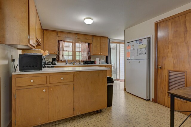 720 Kentland Dr, Neosho, MO 64850 - kitchen featuring freestanding refrigerator, light countertops, light flooring, black microwave, and brown cabinetry