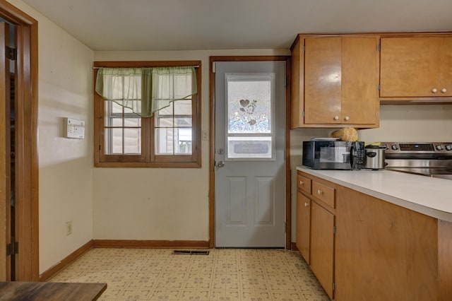720 Kentland Dr, Neosho, MO 64850 - kitchen featuring light floors, stainless steel electric stove, under cabinet range hood, black microwave, and light countertops