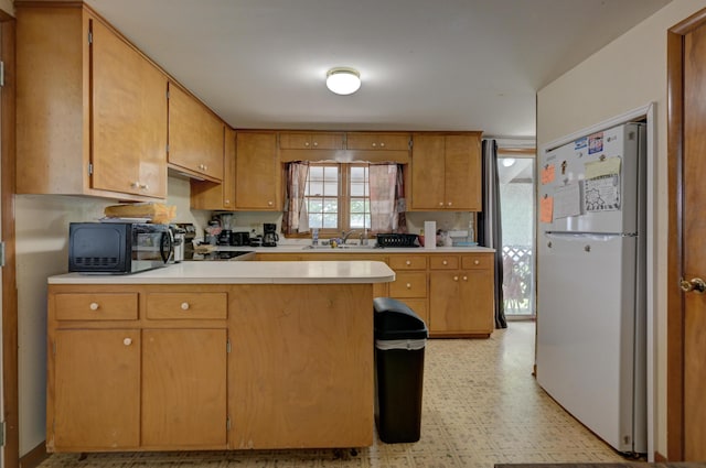 720 Kentland Dr, Neosho, MO 64850 - kitchen featuring freestanding refrigerator, black microwave, a sink, a peninsula, and light countertops