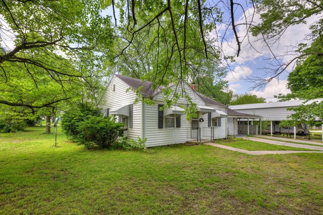 720 Kentland Dr, Neosho, MO 64850 - view of front of house with a front yard, driveway, a chimney, and a carport
