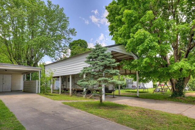 720 Kentland Dr, Neosho, MO 64850 - view of front facade with concrete driveway, a carport, and a front lawn