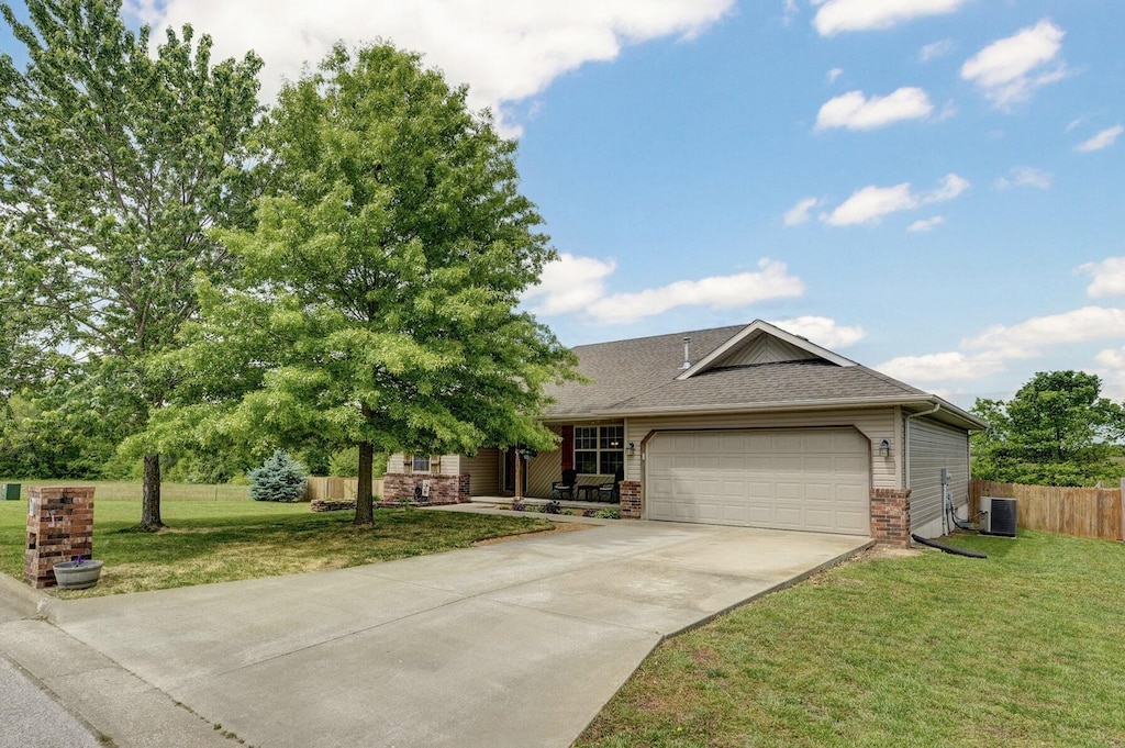 309 Union Hill St, Clever, MO 65631 - view of front of house featuring an attached garage, concrete driveway, brick siding, central AC unit, and roof with shingles