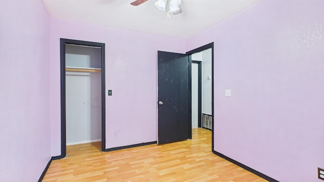 unfurnished bedroom with light wood-style flooring, baseboards, a closet, and a ceiling fan