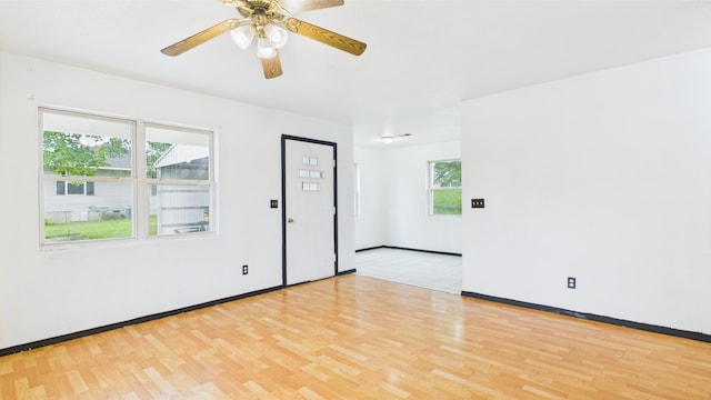 empty room with light wood-style flooring, a ceiling fan, and baseboards