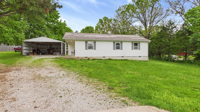 rear view of property featuring crawl space, driveway, a detached carport, and a yard