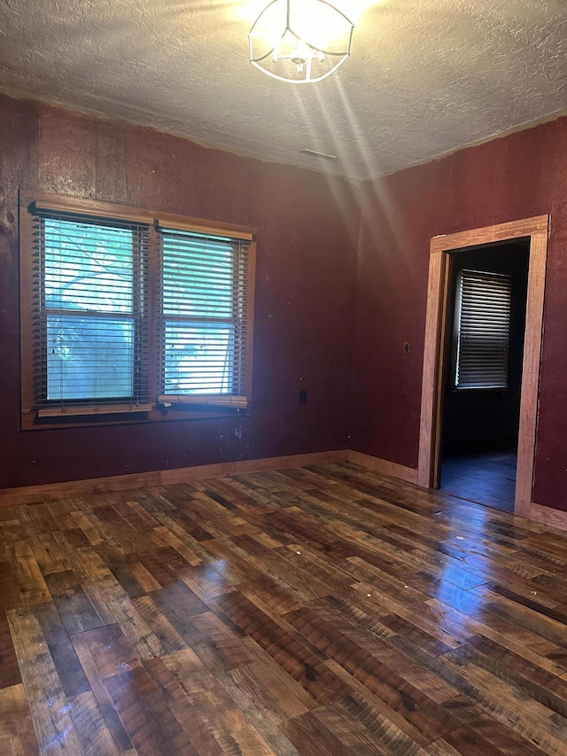 empty room with a textured ceiling and wood finished floors