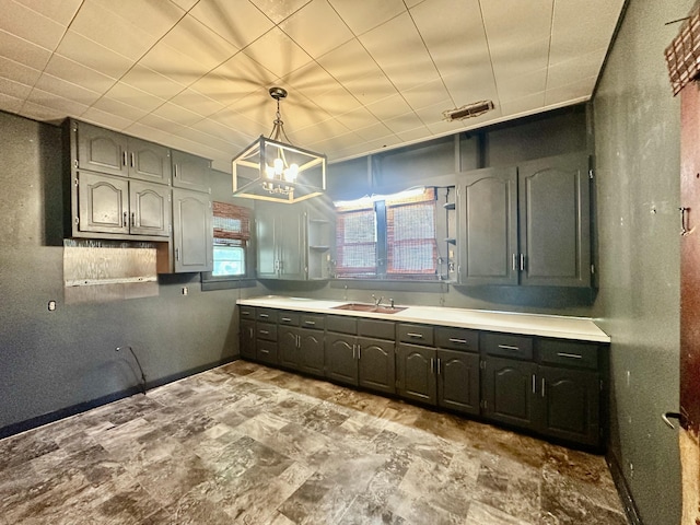 kitchen with a chandelier, hanging light fixtures, a sink, and light countertops