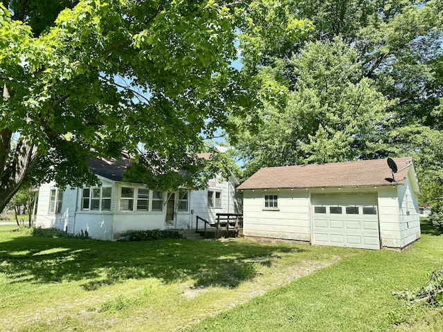 view of grassy yard with a detached garage, an outdoor structure, and driveway