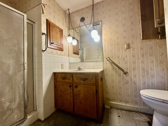 full bathroom with wallpapered walls, a shower stall, toilet, and vanity