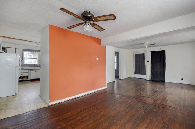 unfurnished living room featuring a ceiling fan, hardwood / wood-style flooring, and baseboards