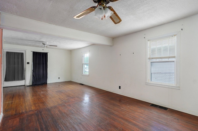 empty room featuring ceiling fan, hardwood / wood-style flooring, a textured ceiling, baseboards, and beam ceiling