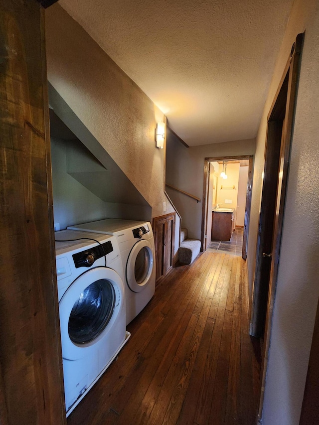 laundry room featuring independent washer and dryer, hardwood / wood-style flooring, a textured wall, and a textured ceiling