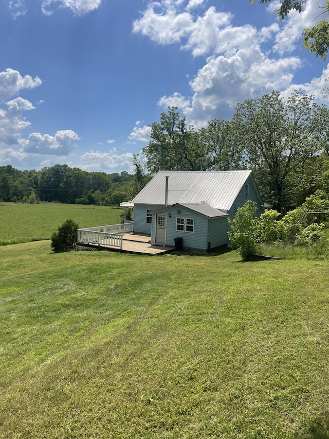 rear view of house featuring a deck, a lawn, and metal roof