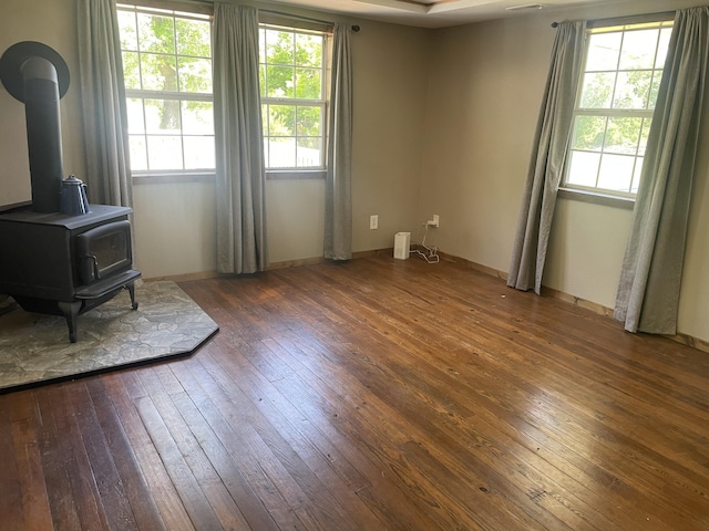 living room with hardwood / wood-style flooring, a wood stove, and baseboards