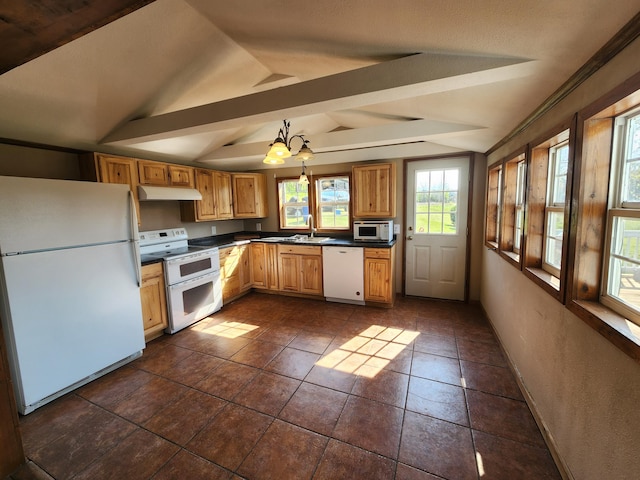 kitchen with white appliances, under cabinet range hood, dark countertops, a sink, and hanging light fixtures
