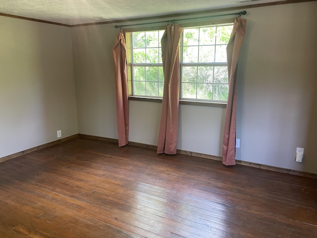 spare room featuring wood-type flooring, healthy amount of natural light, a textured ceiling, baseboards, and crown molding