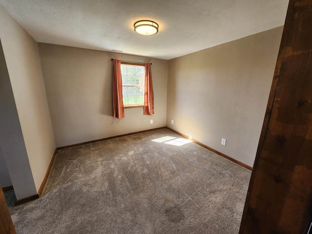 carpeted spare room featuring baseboards