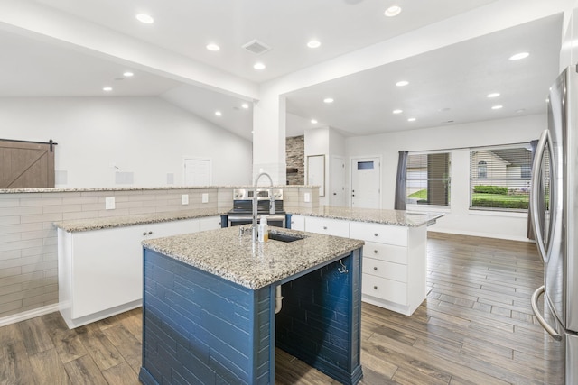 1970 Pointe Royale Dr, Branson, MO 65616 - kitchen with a center island with sink, freestanding refrigerator, wood finished floors, white cabinetry, and a sink
