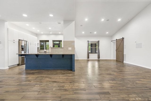 1970 Pointe Royale Dr, Branson, MO 65616 - kitchen with stainless steel fridge with ice dispenser, a barn door, a peninsula, a kitchen breakfast bar, and white cabinetry